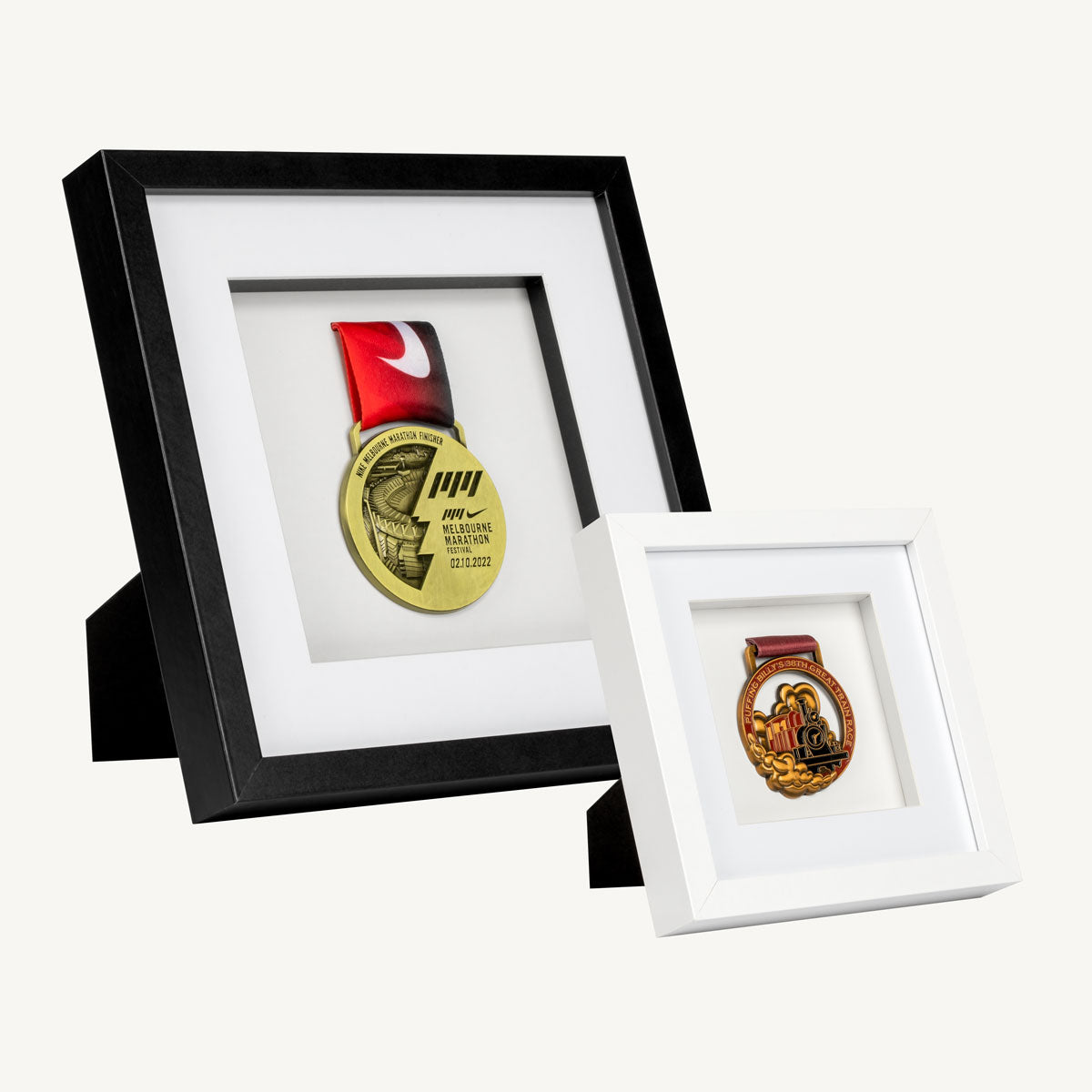 2 framed medals. ONe frame is bigger than the other and is black. The smaller frame is white.