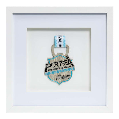 Silver medal from the Portsea Running festival framed in a white square frame, front on angle