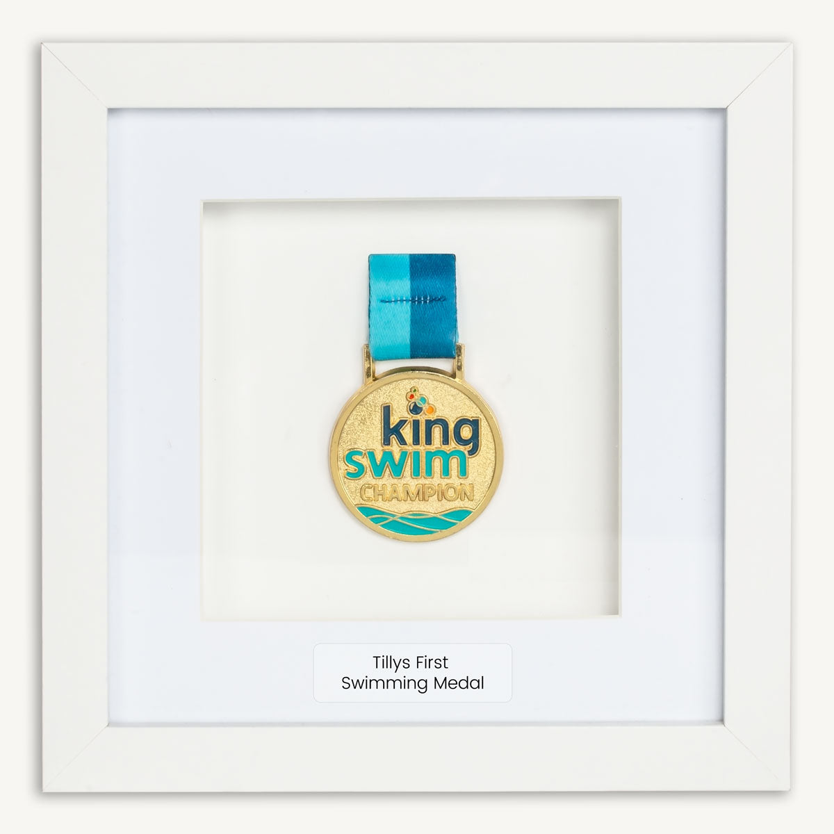 Kids Swimming medal in white frame. Medal says King Swim Champion. Frame personalised with Tillys First Swimming Medal.