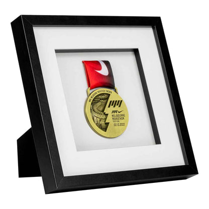 Gold medal from the Melbourne Marathon framed in a Black square frame, on angle