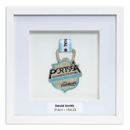 Silver medal from the Portsea Running festival framed in a white square frame, front on angle. With Personalisation Label. 