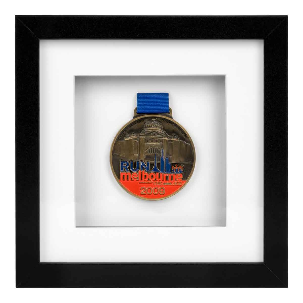 Red, Blue and gold medal from Run Melbourne in 2009 framed in a Black square frame, front on angle