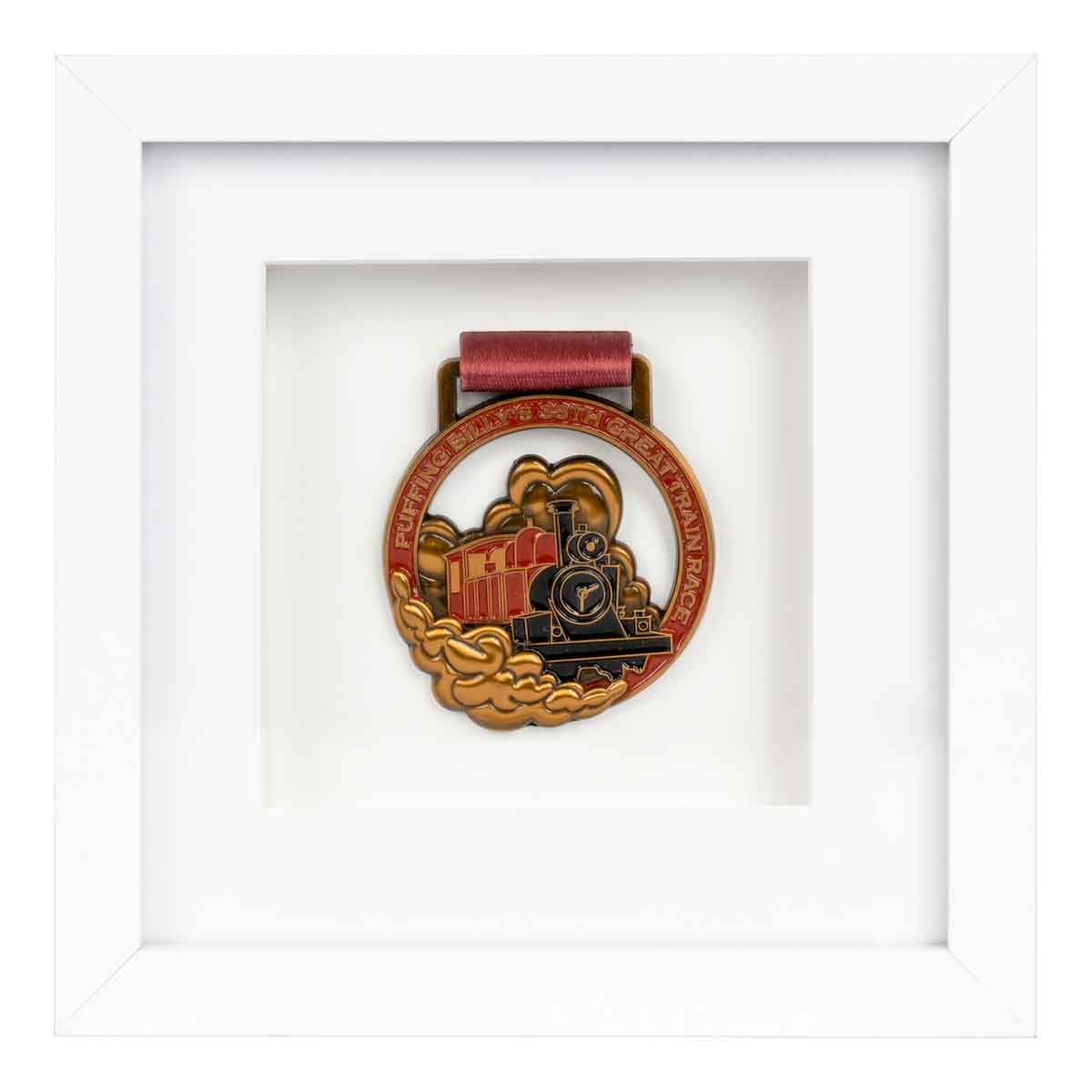 Gold medal from the Puffing Billy running race showing a steam train framed in a White square frame, front on angle